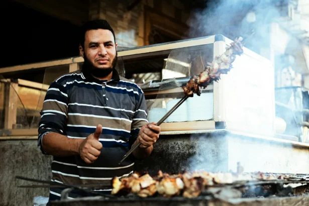Street vendor in Cairo grilling delicious meat skewers on an outdoor barbecue.