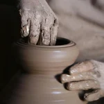 Detailed view of a potter's hands shaping clay pottery on a spinning wheel in Cairo, Egypt.