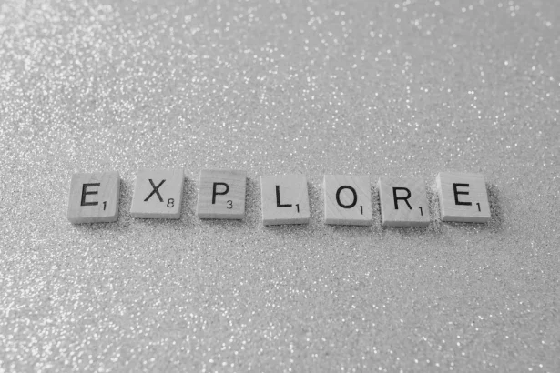Monochrome Scrabble tiles spelling 'EXPLORE' on a glitter background.
