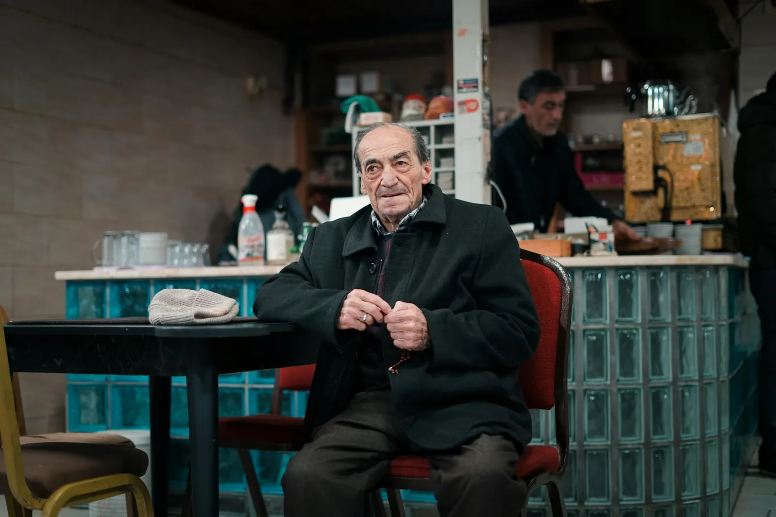 An elderly man sits comfortably in a cozy coffee shop, enjoying the warm atmosphere.