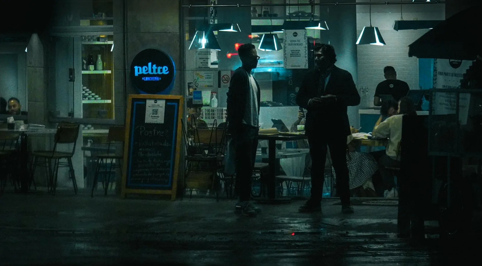 Moody and atmospheric street view of a bustling nighttime restaurant scene.