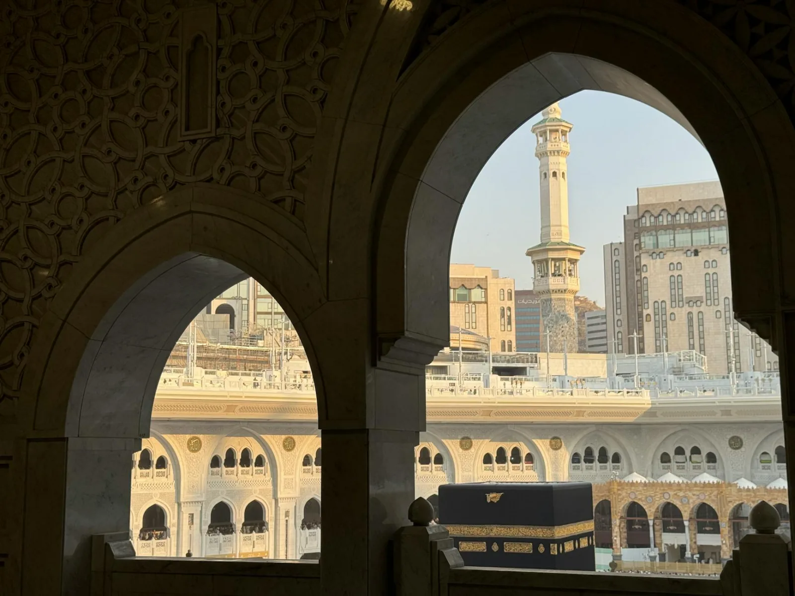 A serene view of the Kaaba through ornate archways in Mecca, Saudi Arabia.