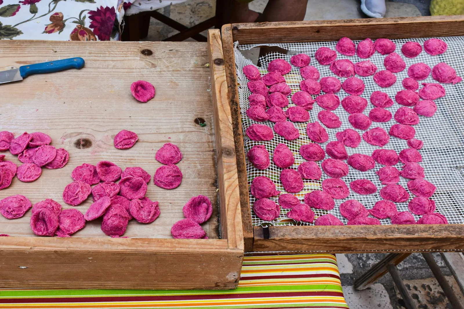 Freshly made beetroot orecchiette pasta drying outdoors in Apulia, Italy.
