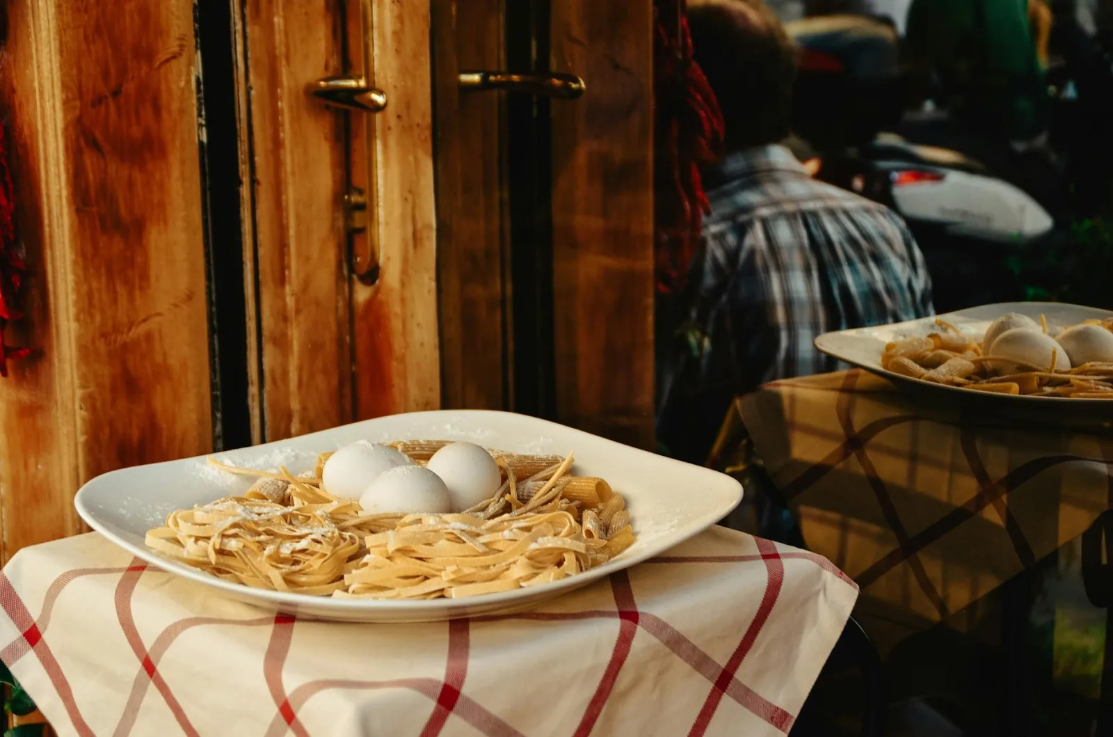 A plate of fresh pasta with eggs is displayed outside a Rome restaurant, showcasing Italian cuisine.