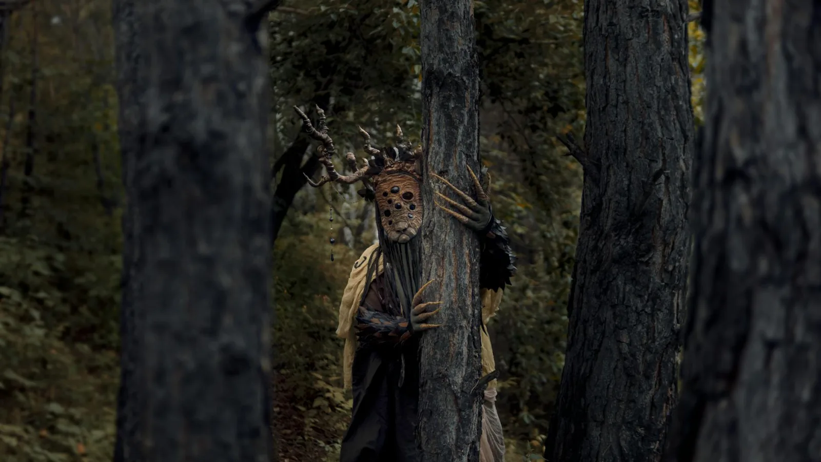 A mysterious and eerie forest scene with a costumed figure among the trees, evoking a sense of suspense.