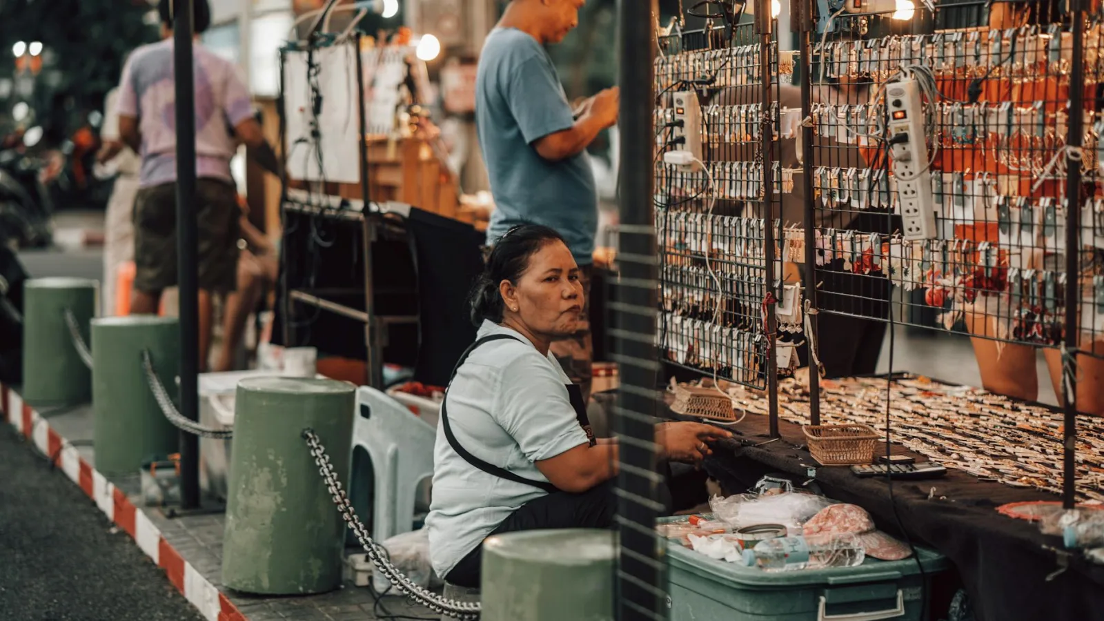 A bustling street market scene with vendors selling various merchandise under warm daylight.