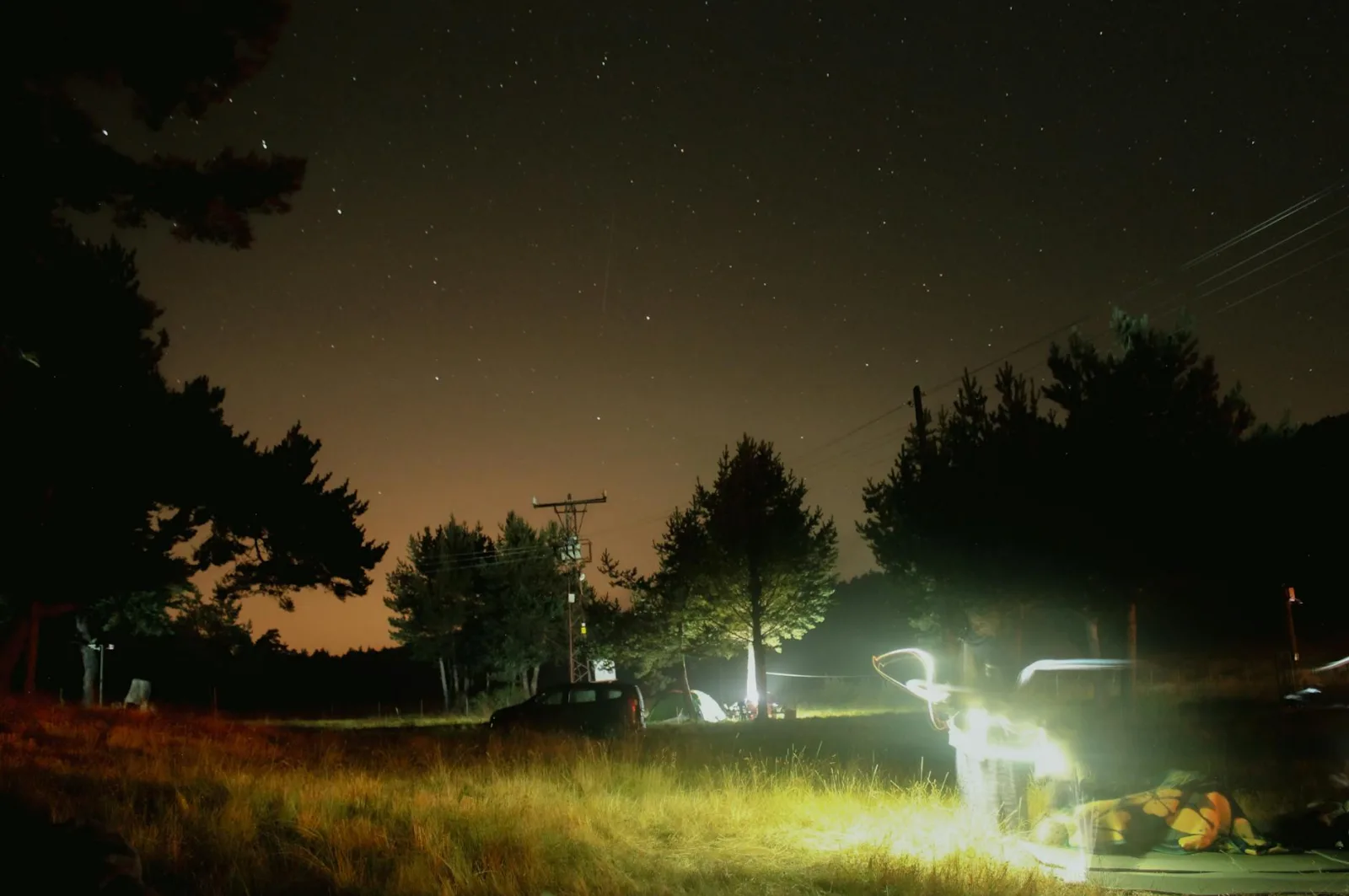 A serene night camping scene with tents under a starry sky in a forest setting.