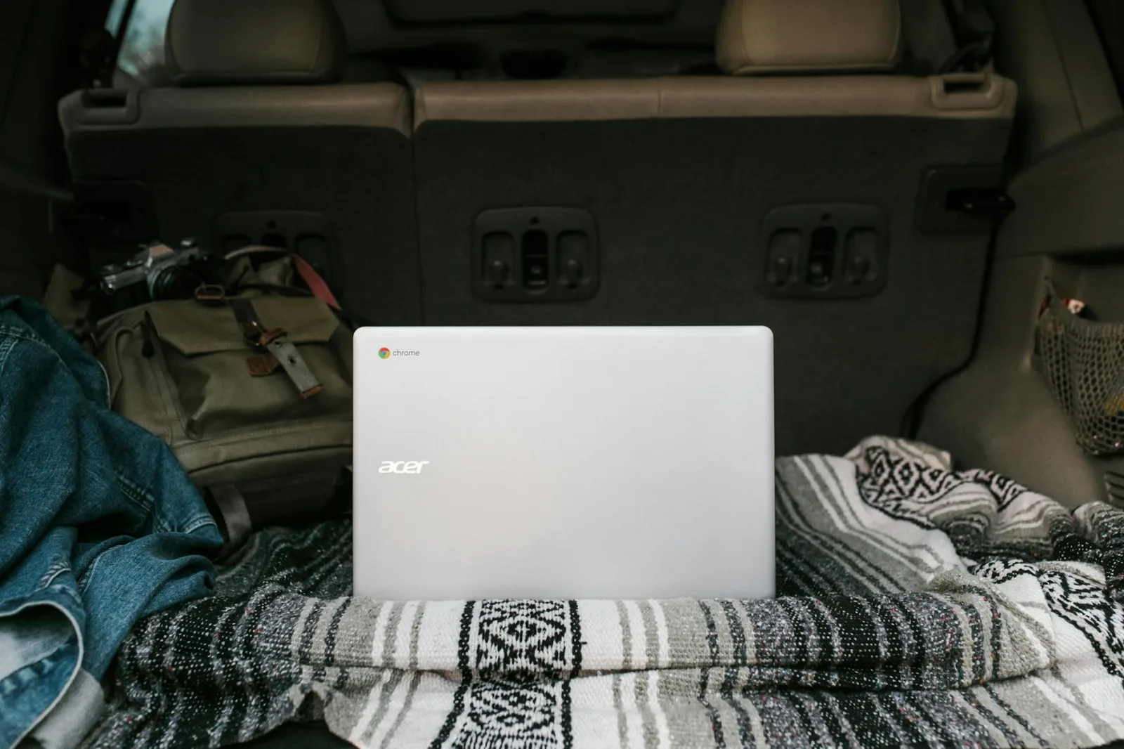 Laptop setup in a car trunk with cozy blanket for remote work travel ease.