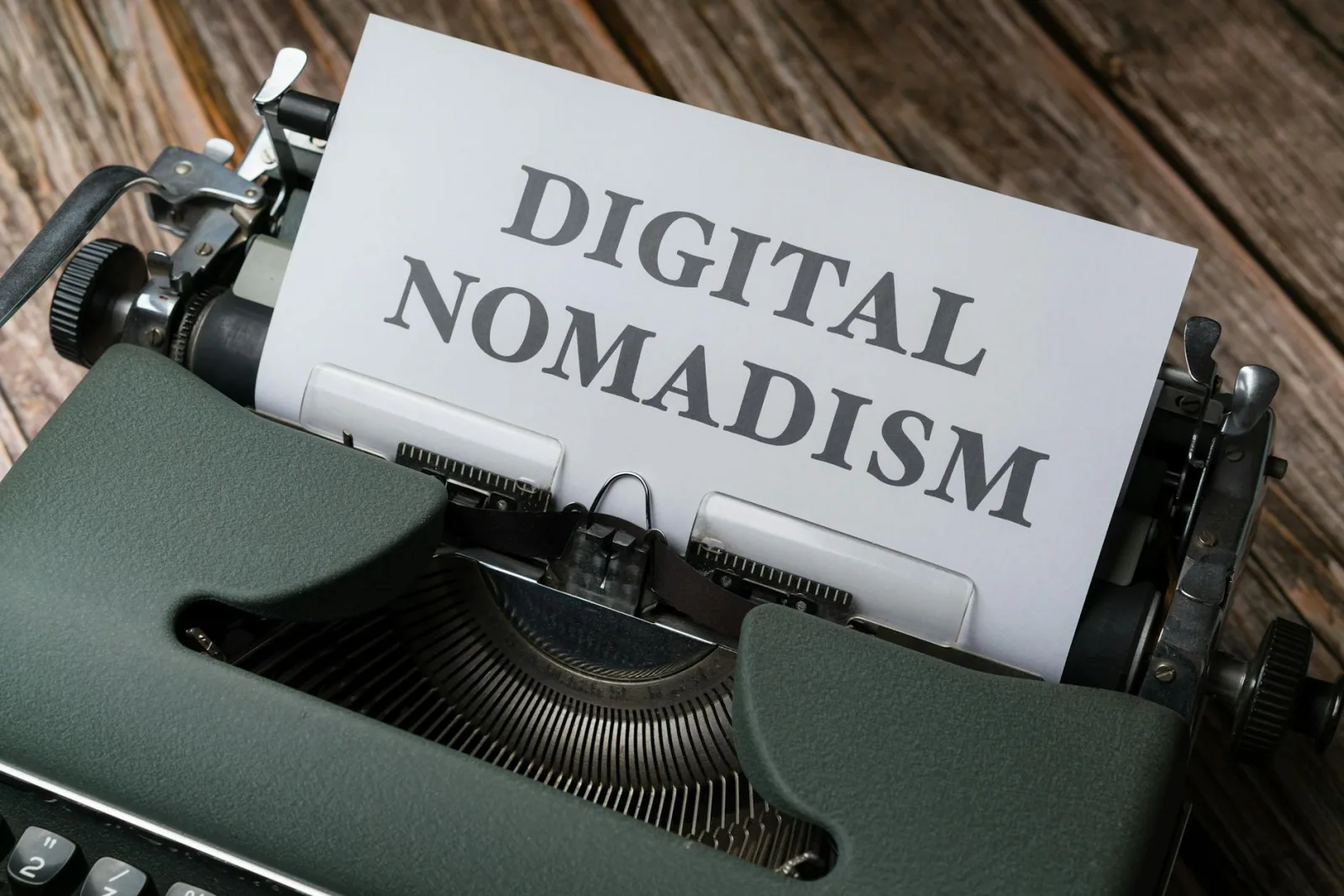 A classic typewriter with a paper reading 'Digital Nomadism' on a wooden desk.