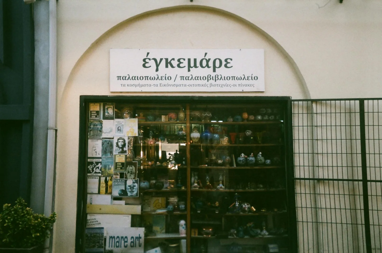 Explore a vintage storefront in Ayvalık, Turkey featuring ceramics and books.