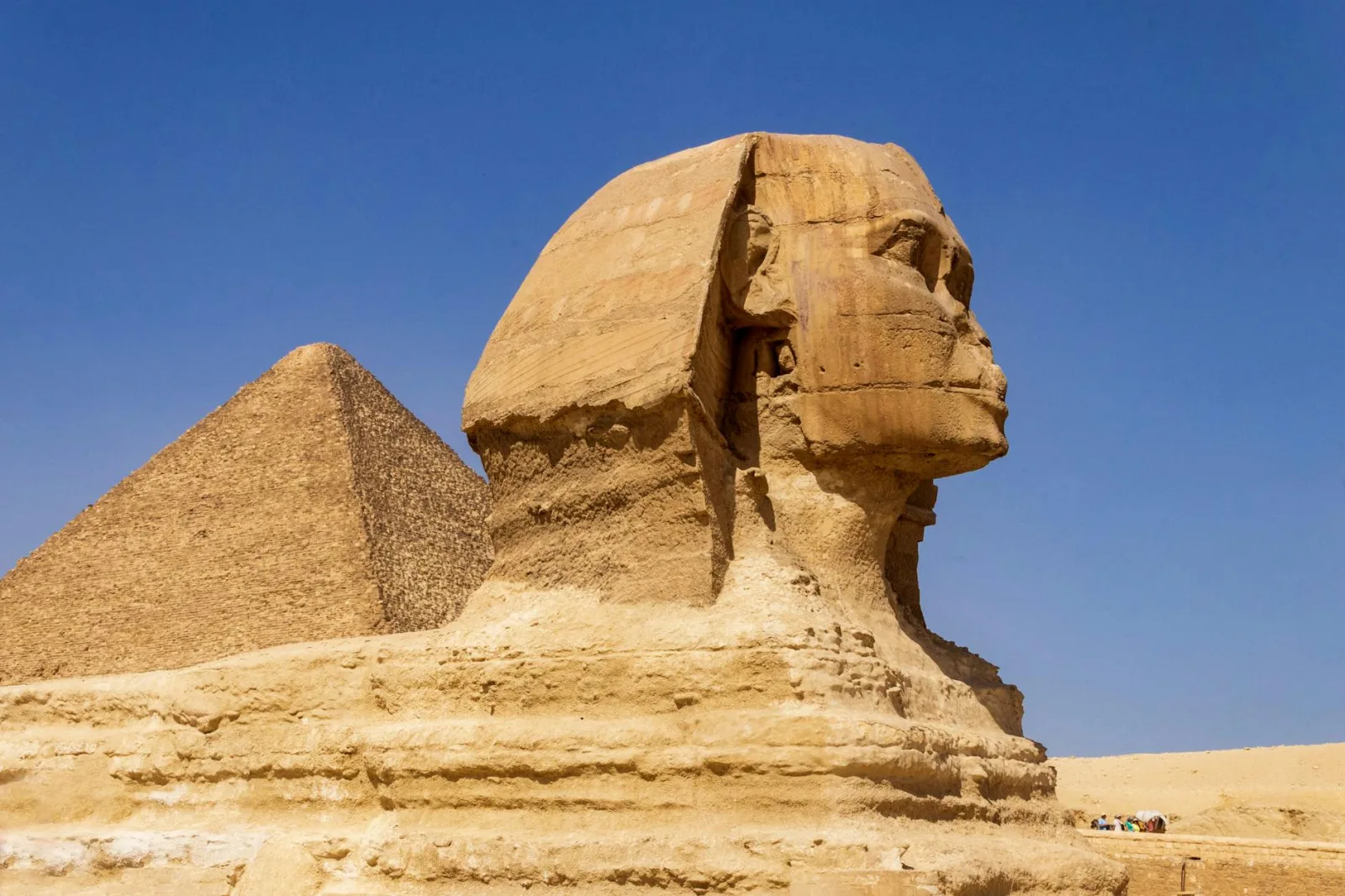 Majestic view of the Great Sphinx and Pyramid against a clear blue sky in Giza, Egypt.