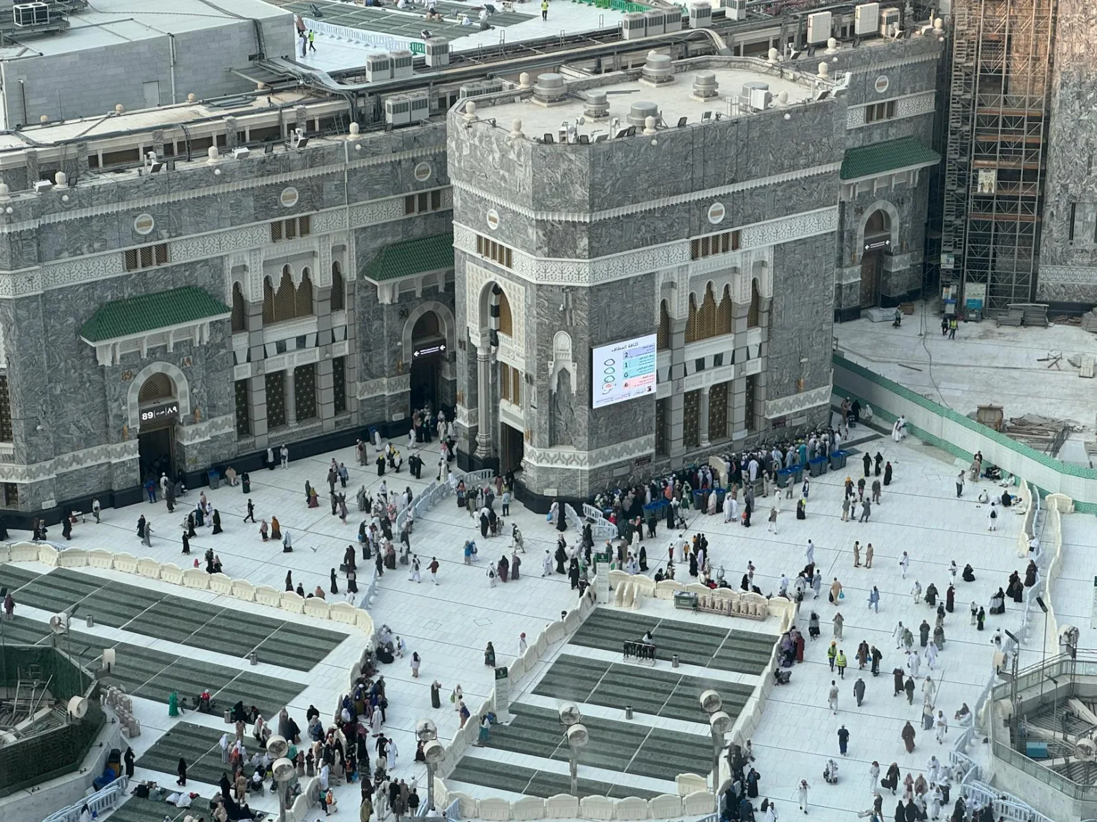 Aerial view of people around Masjid al-Haram in Mecca, showing its architecture and bustling atmosphere.
