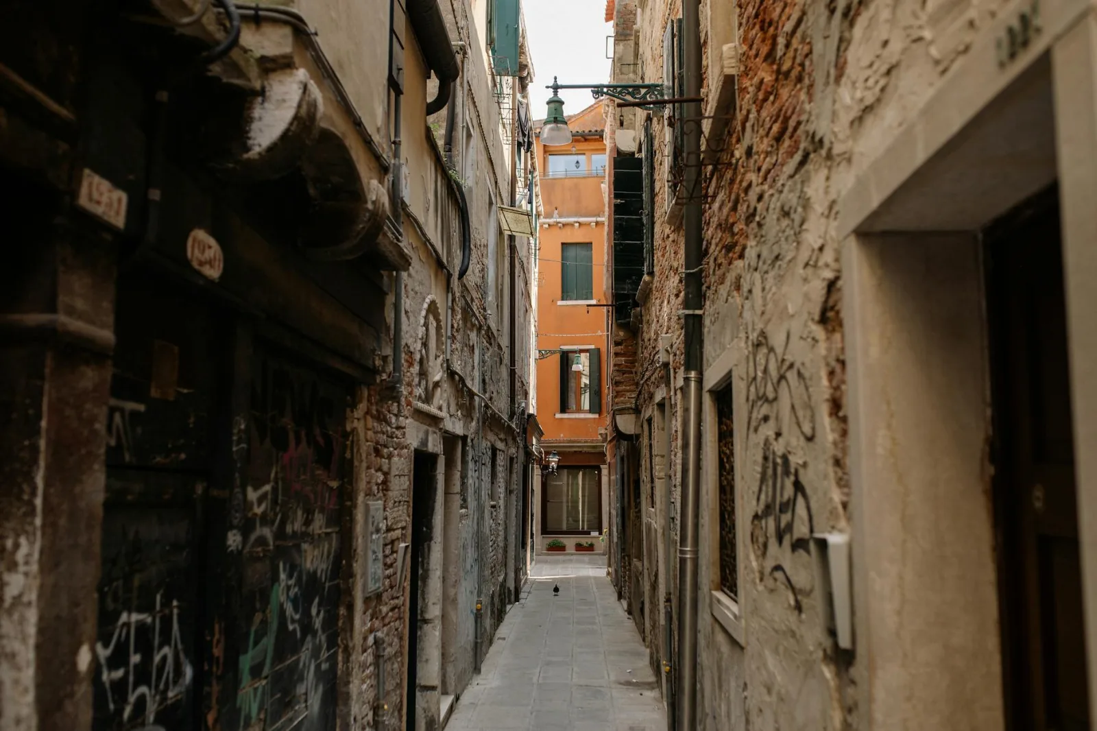 A narrow alleyway with old brick facades and graffiti in a historic city.