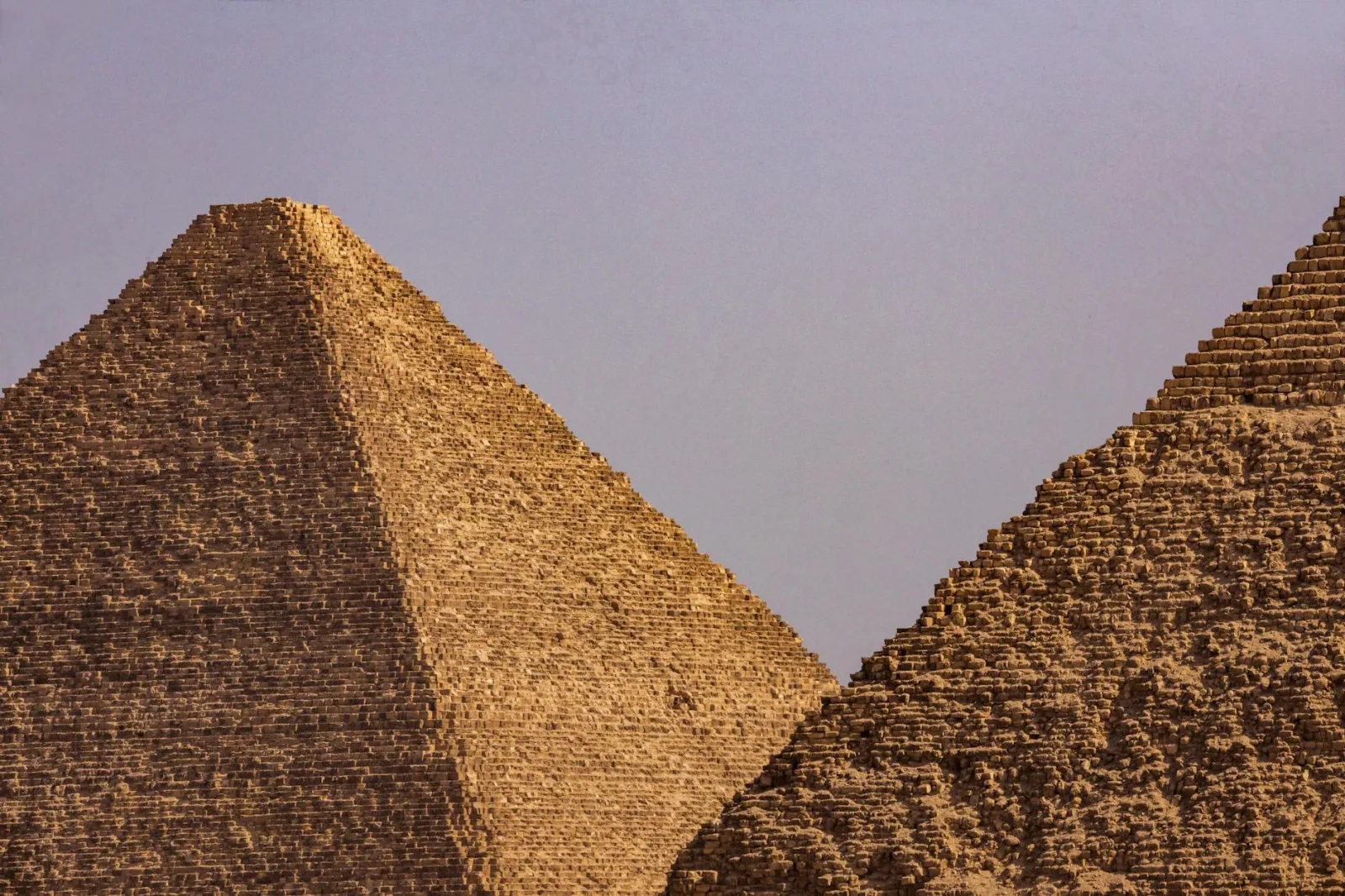 A close-up view of two iconic Egyptian pyramids under a clear blue sky.