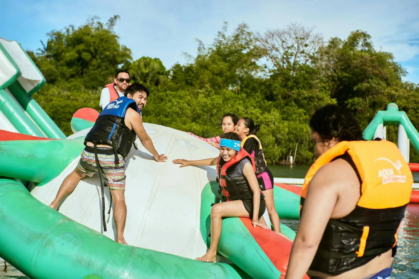 Group enjoying summer day at a water park with inflatable structures. Perfect for travel and leisure imagery.