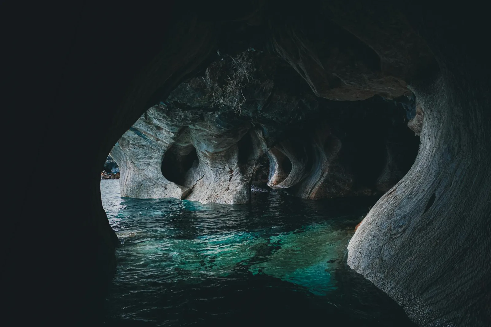 Explore the serene beauty and mystery of an eroded cave with clear water reflections.