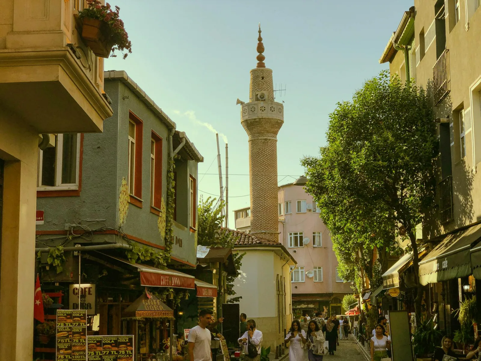 Vibrant street scene in Istanbul showcasing a historic minaret, shops, and people.