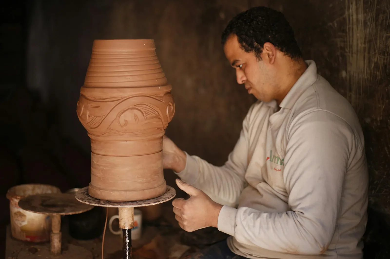 A potter in Cairo skillfully shapes earthenware pottery with attention to detail.