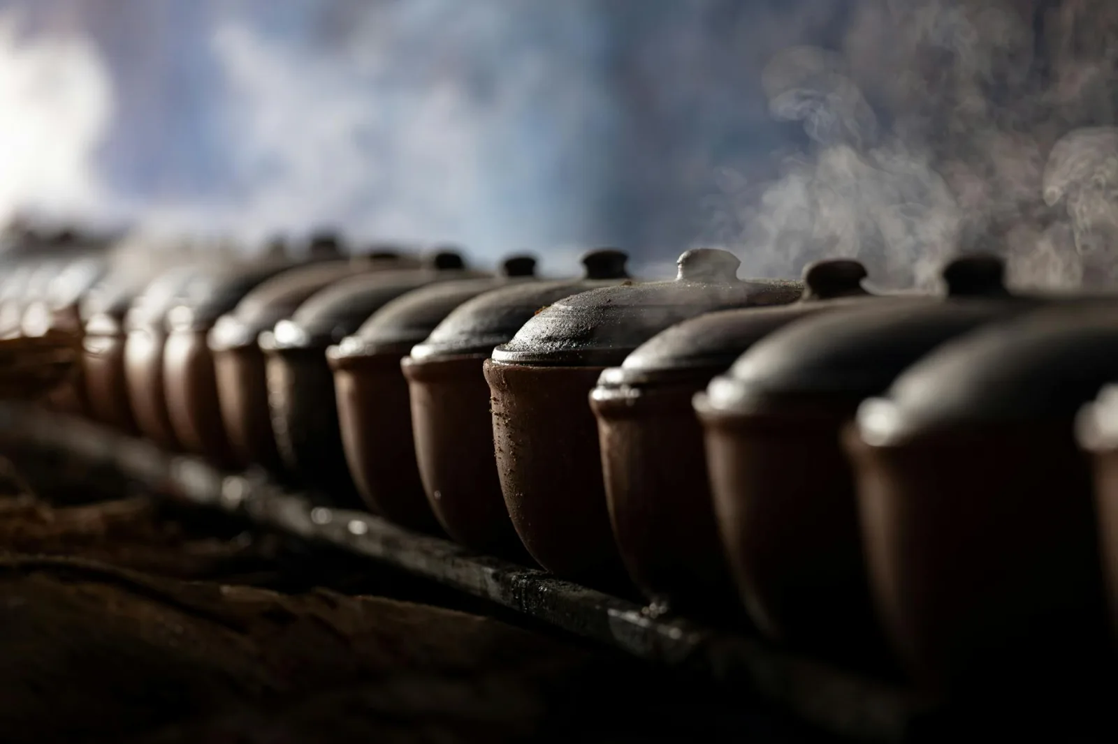 A row of steaming clay pots traditionally used in Vietnamese cooking, evoking cultural culinary practices.