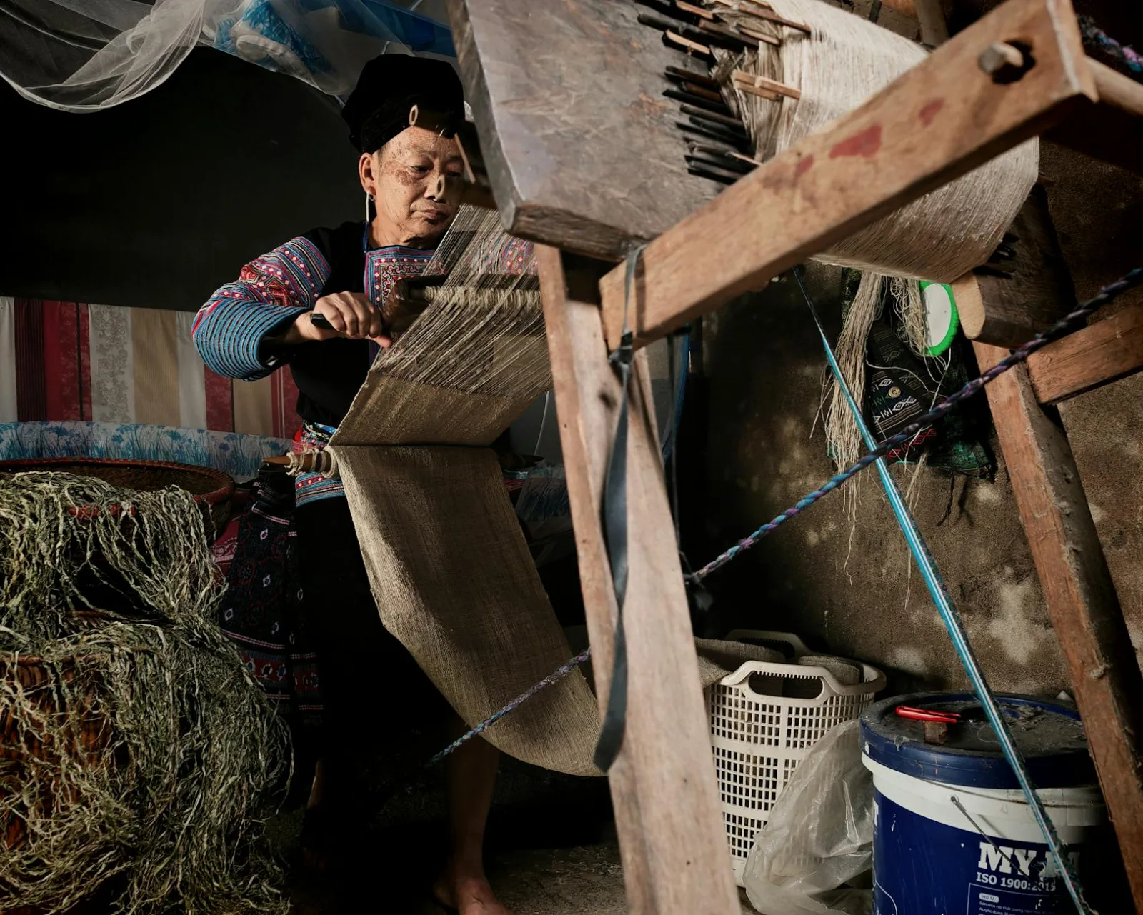 A skilled artisan weaving fabric on a traditional loom in an indoor setting.