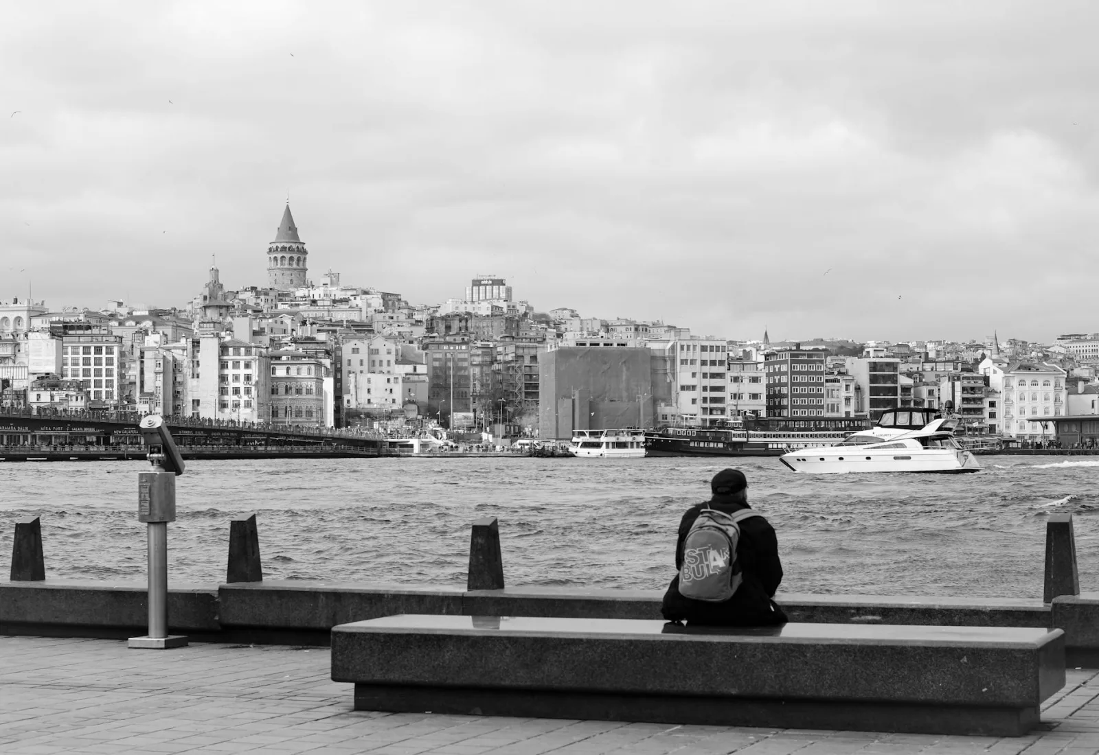 A serene black and white waterfront view with Galata Tower in the distance.