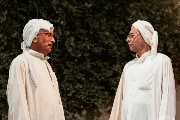 Elderly men wearing traditional Iranian attire engage in conversation outdoors.