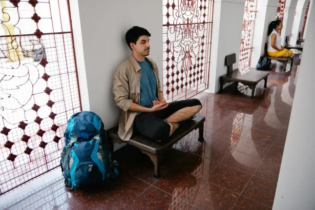 A person meditating indoors, surrounded by stained glass art in a peaceful setting.