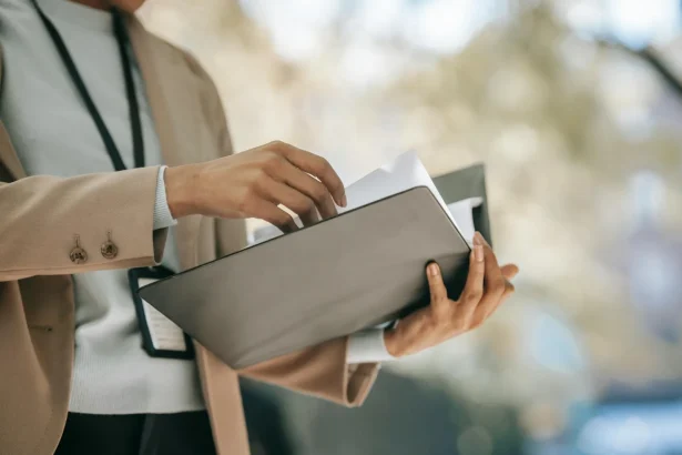 Crop anonymous female entrepreneur in elegant jacket with badge looking through papers in folder
