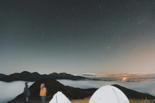 A breathtaking campsite with tents under a star-filled sky and mountain silhouettes.