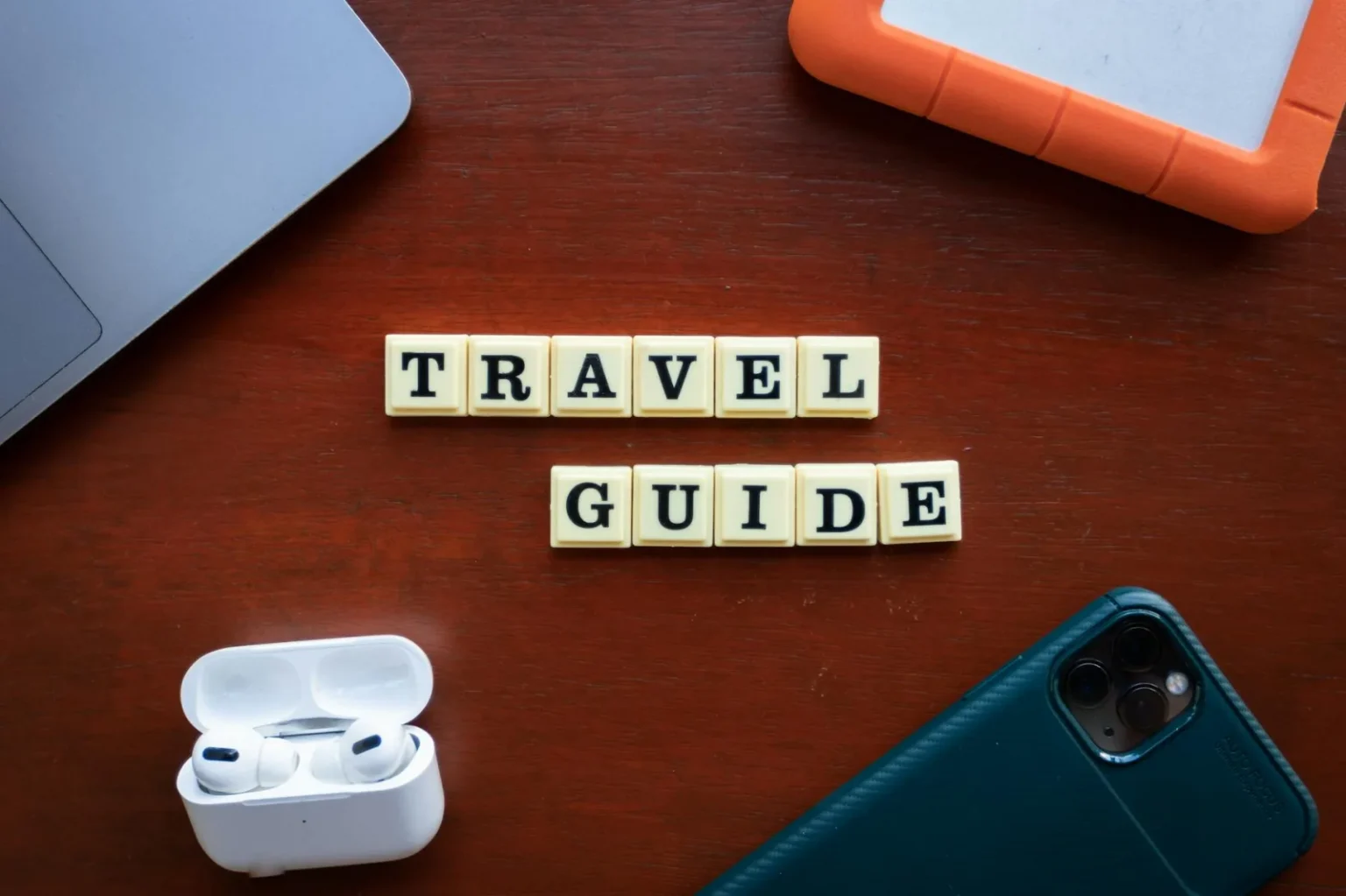 Flat lay of travel guide concept with smartphone, laptop, and headphones.