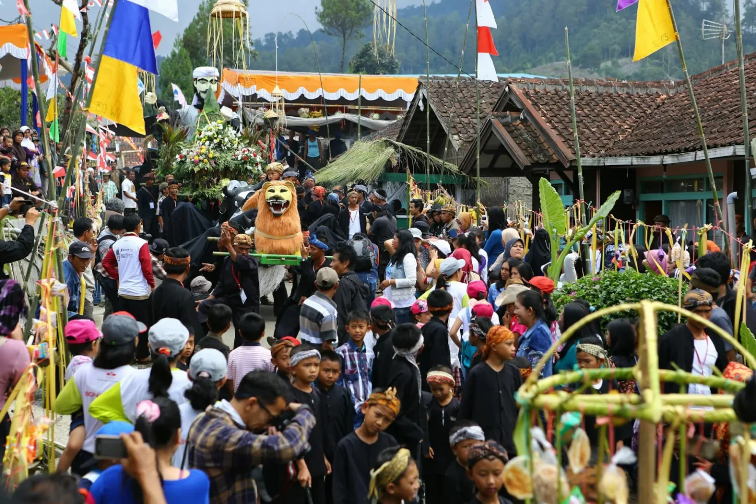 Crowds gather for a traditional cultural festival in Lembang, showcasing vibrant costumes and decorations.