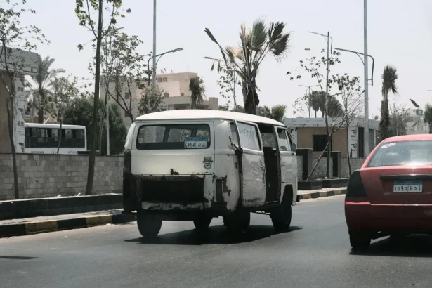 A scene of urban life featuring a vintage van and red car on a street in Cairo, Egypt.