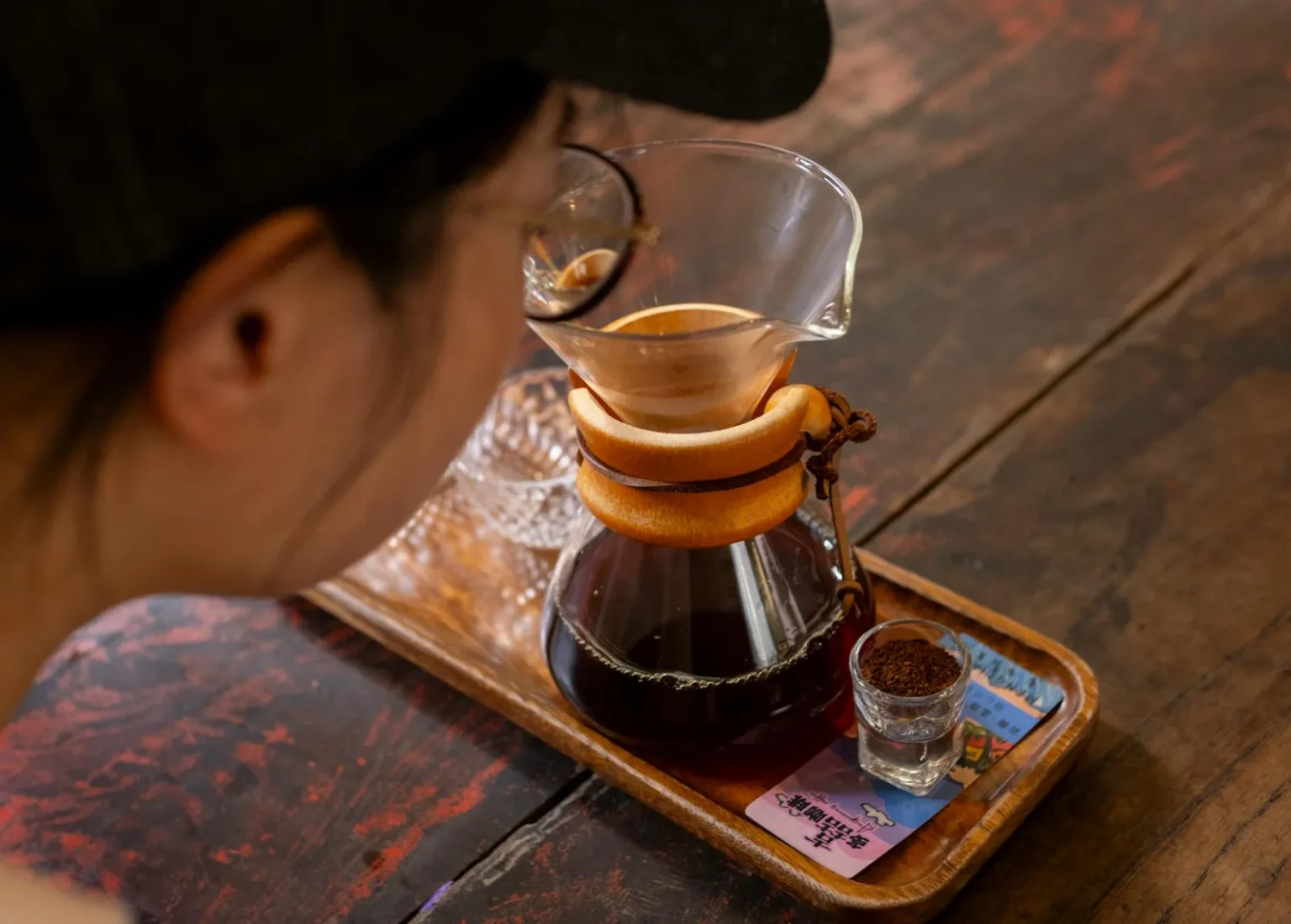 A person brewing artisan coffee with a Chemex in a Yunnan café, capturing the essence of craftsmanship.