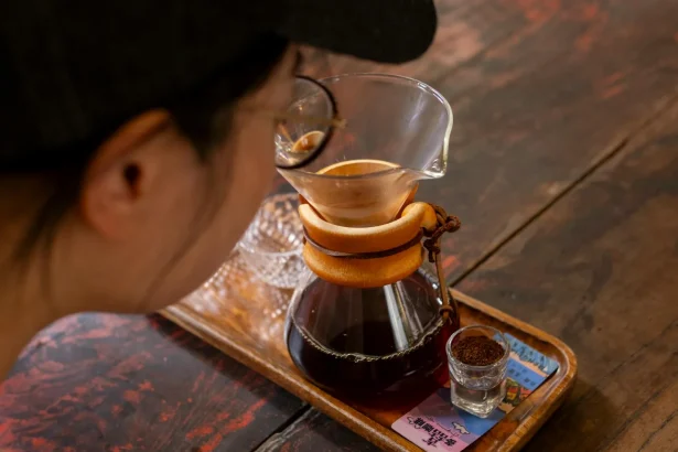 A person brewing artisan coffee with a Chemex in a Yunnan café, capturing the essence of craftsmanship.