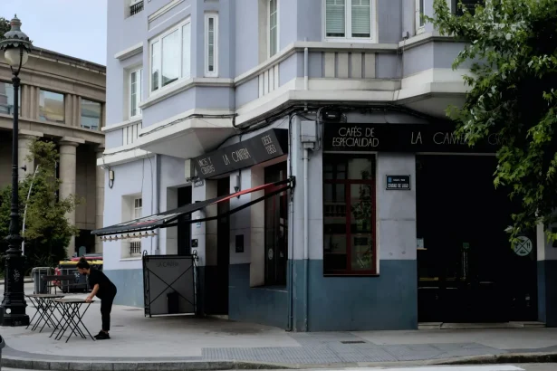 Street view of a café in A Coruña, showcasing urban life with a waitress setting tables.