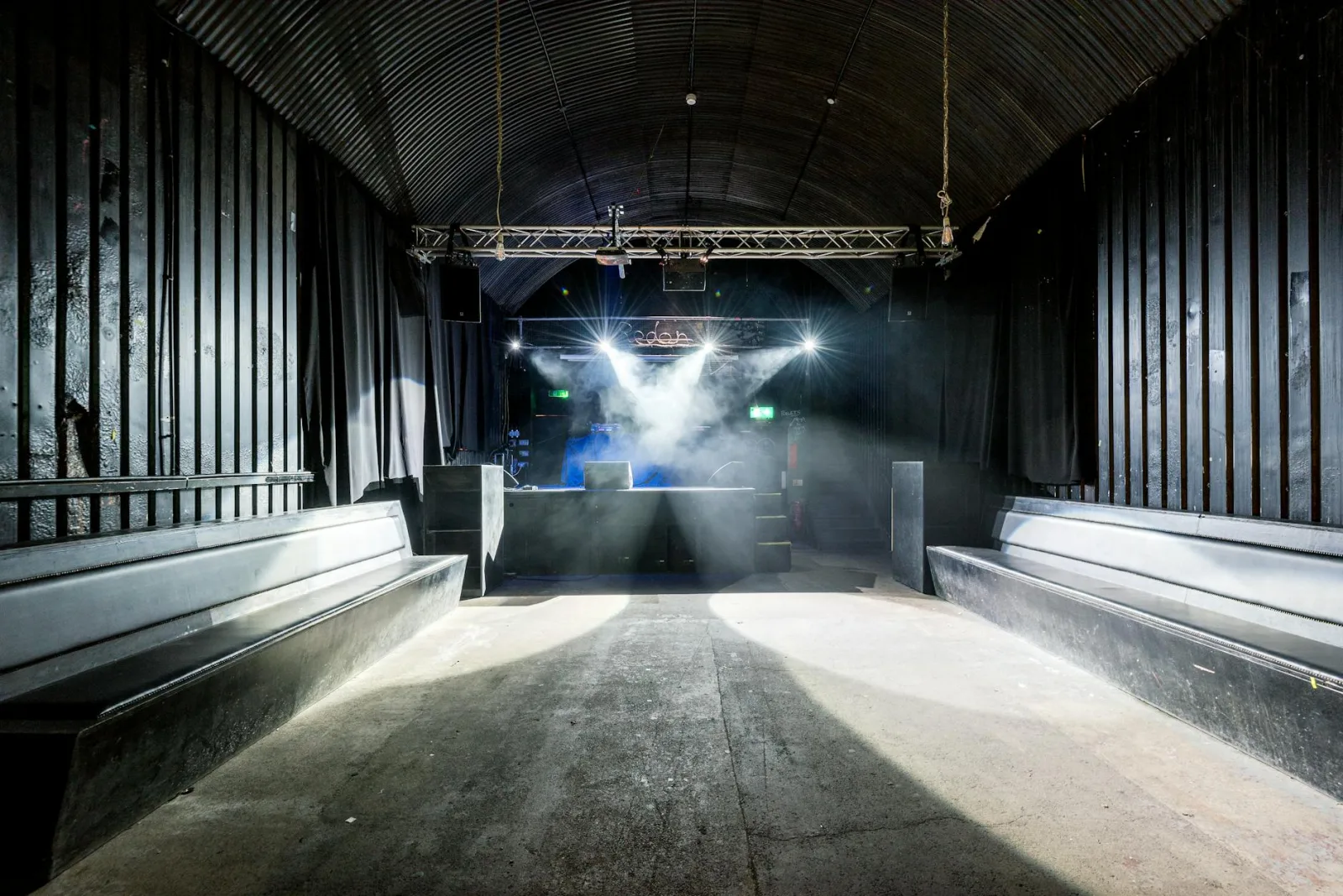 A deserted nightclub featuring stage lighting and seating, highlighting its industrial design.