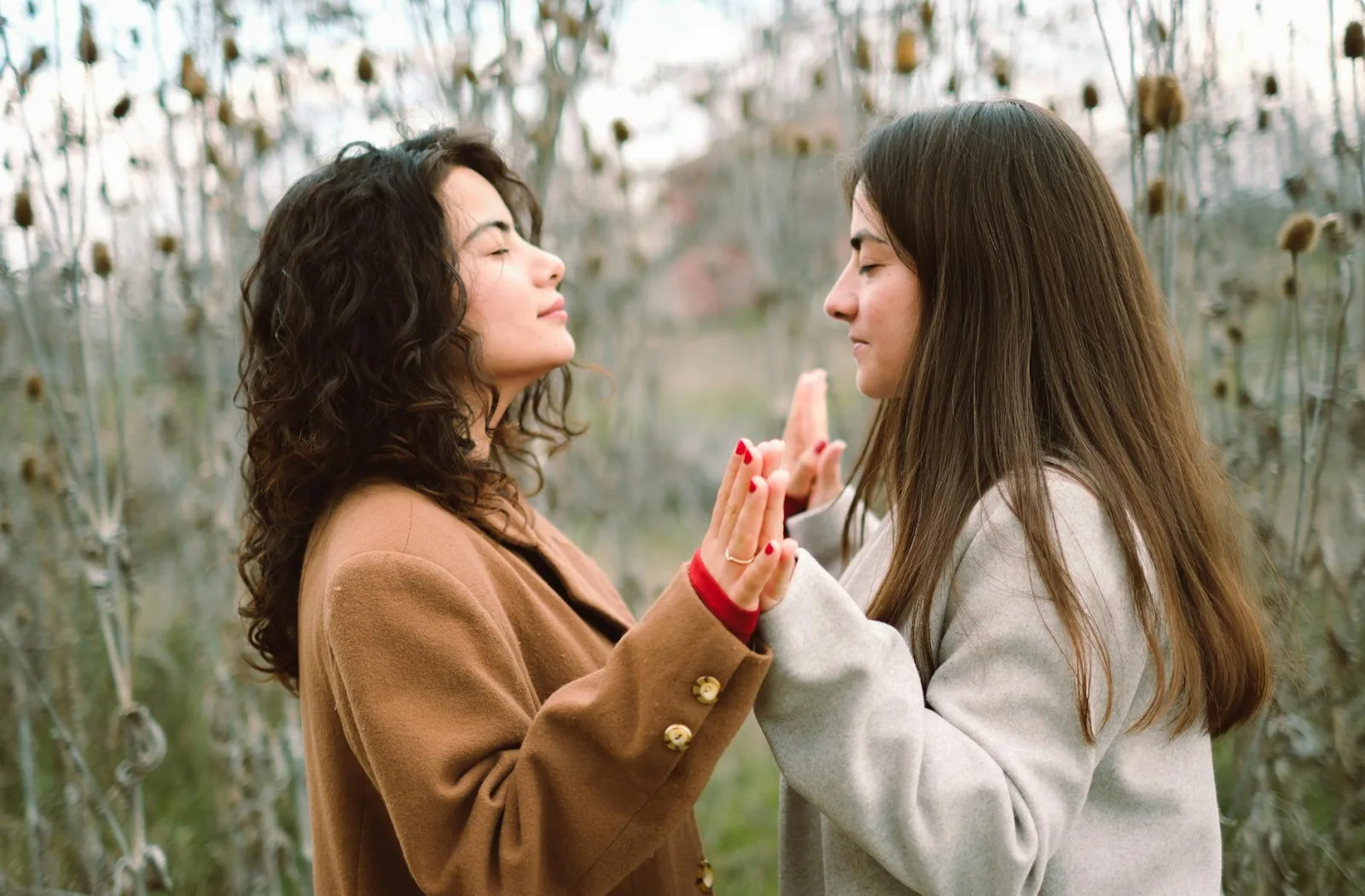 Two young women engage in a mindful meditation practice in a serene natural setting, fostering relaxation and connection.