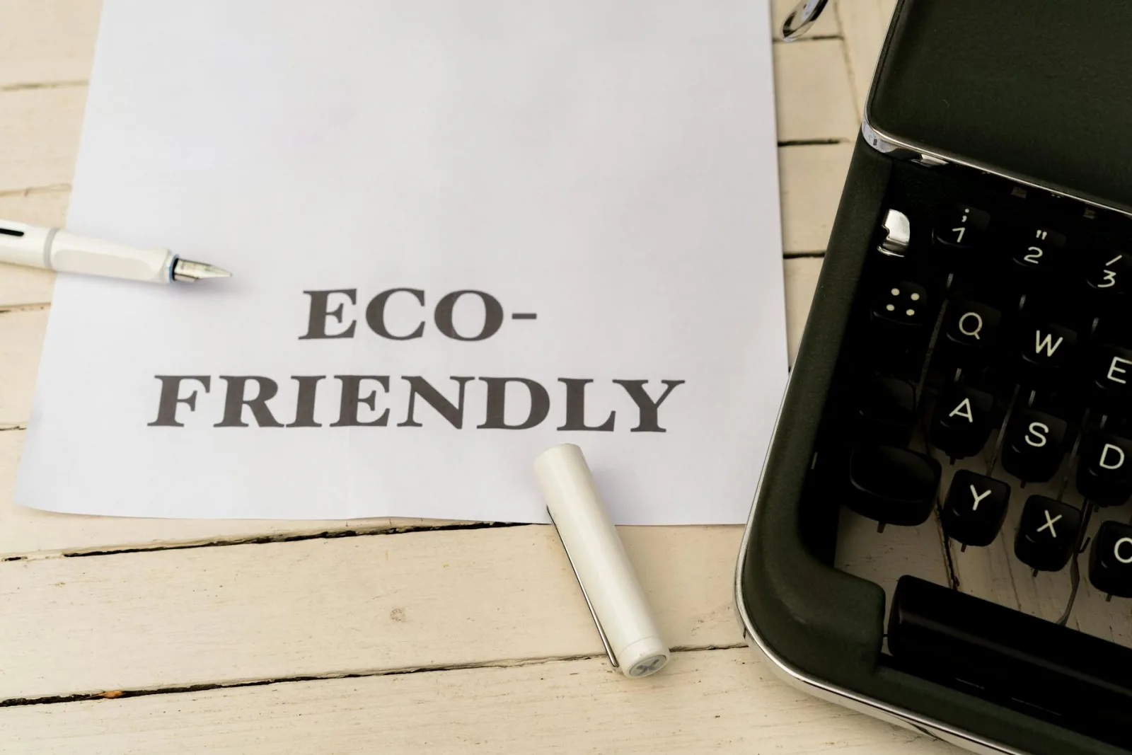 Image of eco-friendly text on paper with a vintage typewriter and pen on a wooden desk.