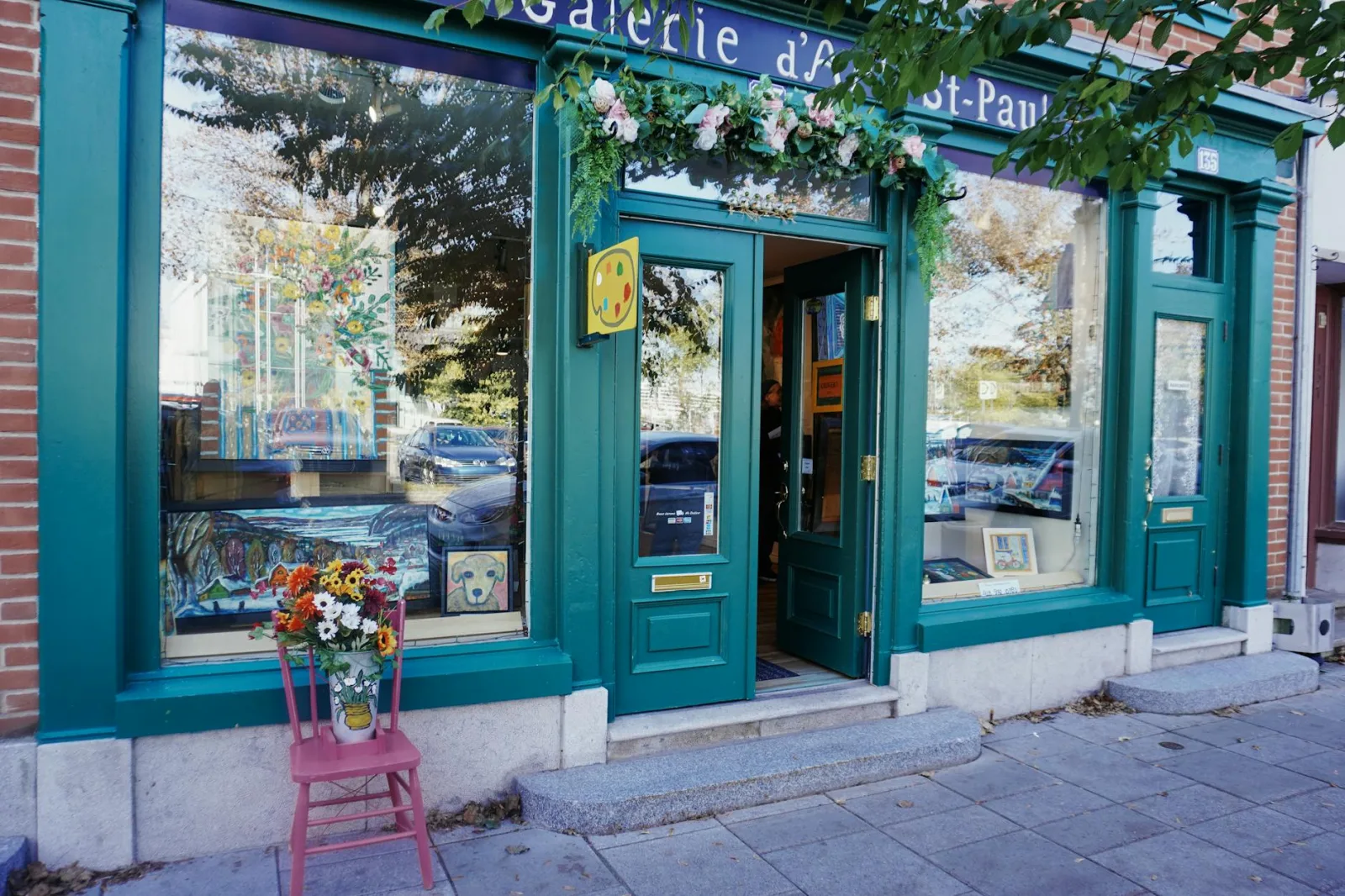 Art gallery entrance with vibrant flowers and artwork on display, showcasing a unique creative vibe.