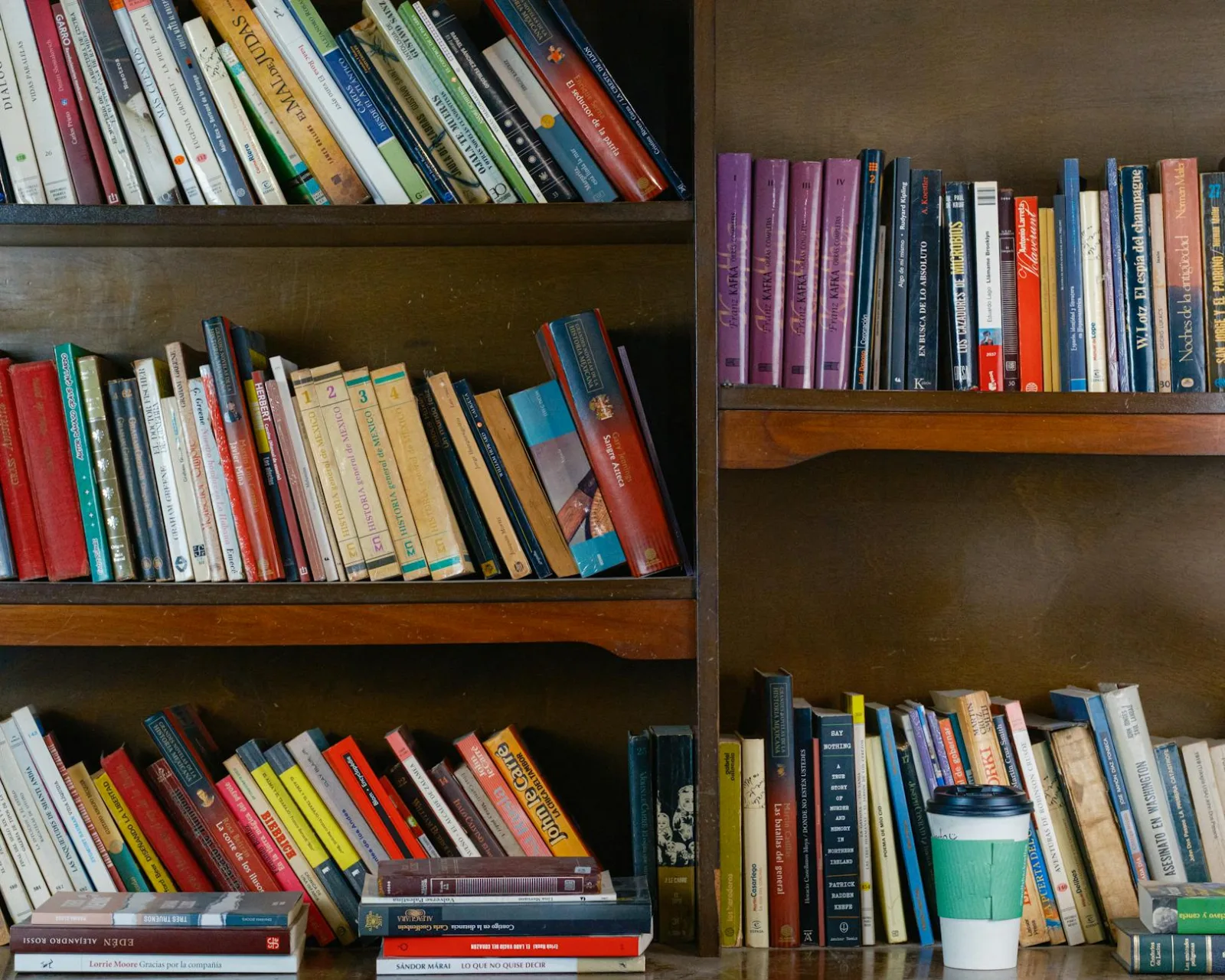 A warm library setting with filled bookshelves and a coffee cup on the table.