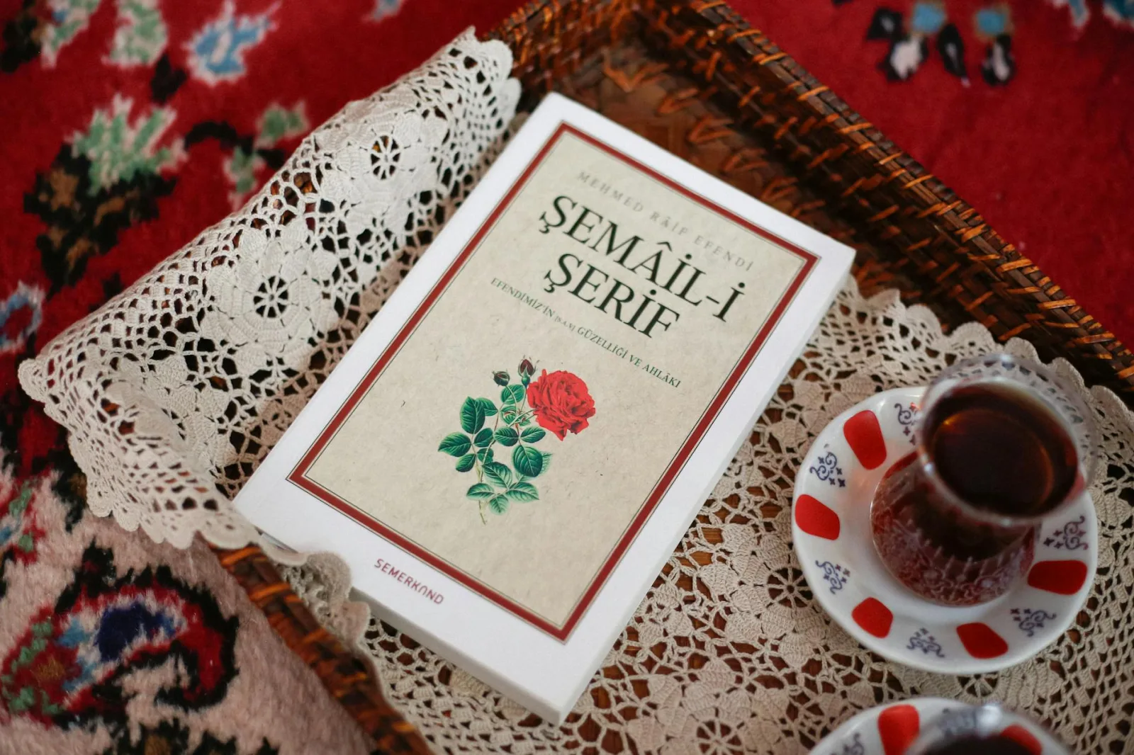 A cozy setting featuring Turkish tea served with a Semail-i Serif book on a decorative lace tray.