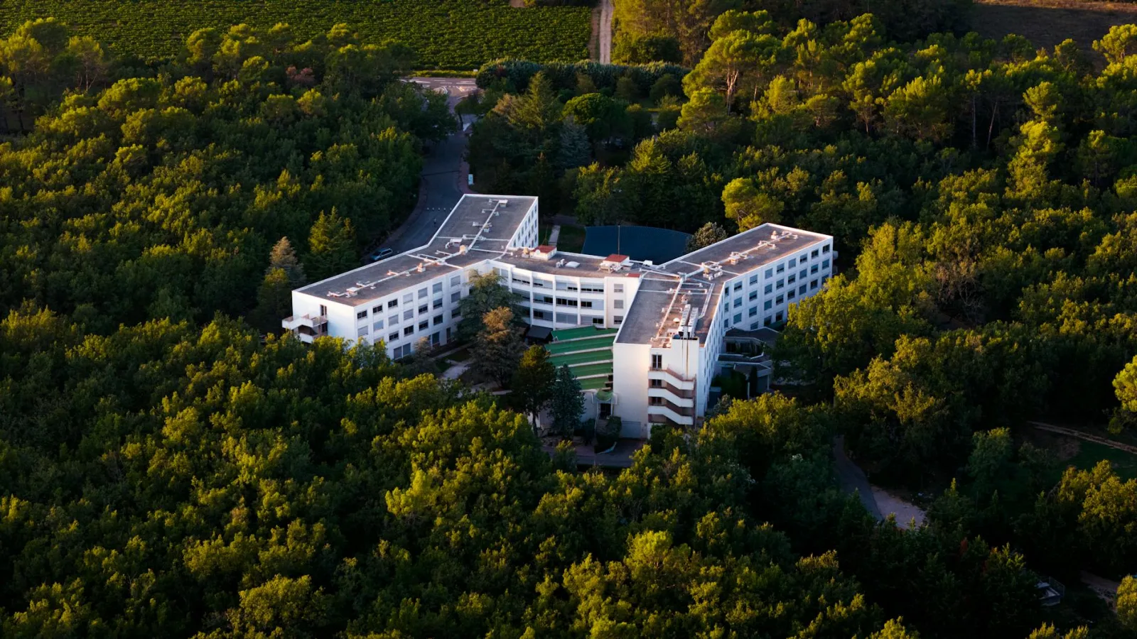 Aerial shot of a modern hotel nestled in a lush green forest.