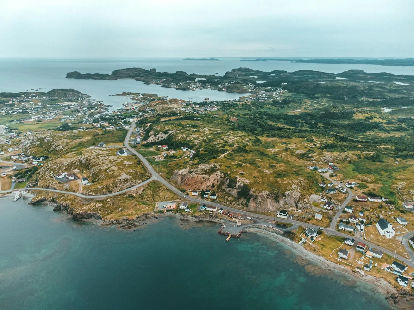 Scenic aerial view of a coastal town surrounded by lush landscapes and sea.
