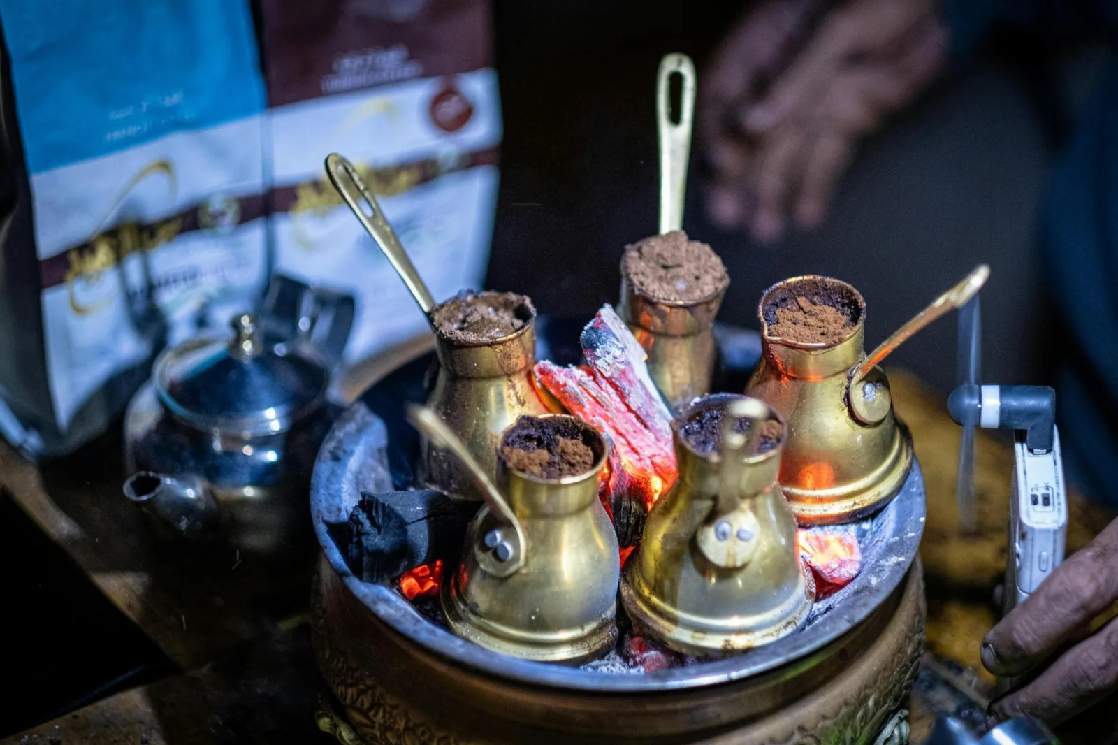 Five Turkish coffee pots brewing over hot coals, creating a warm ambiance.