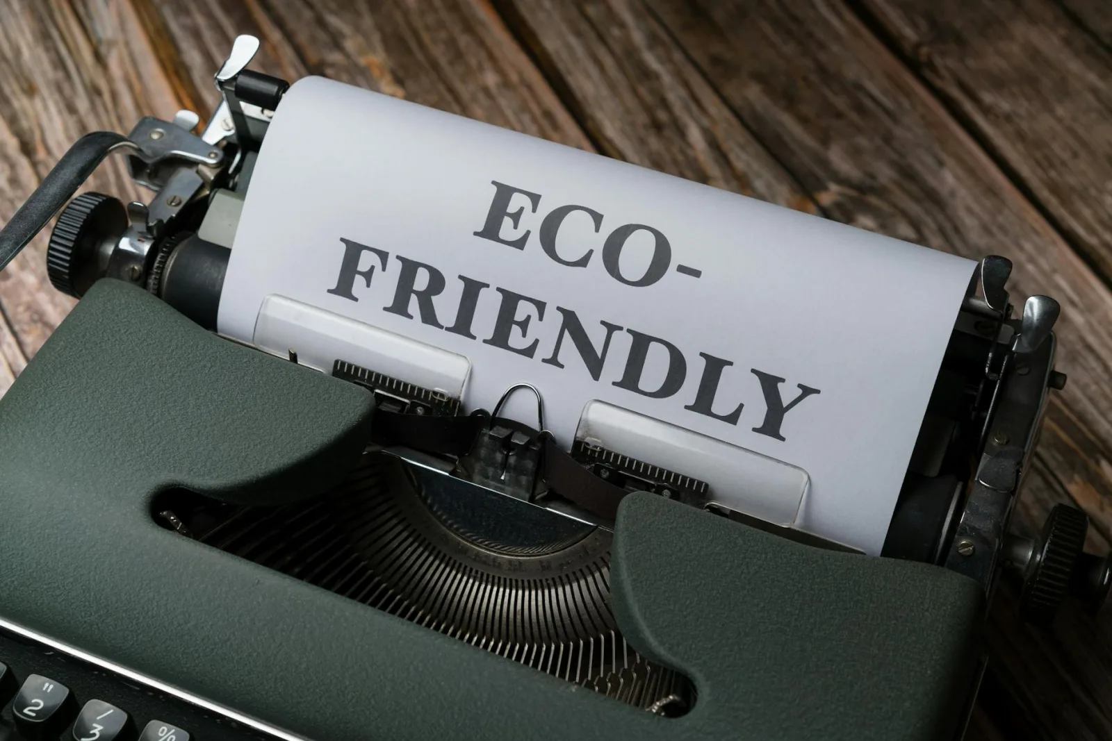 Close-up of a vintage typewriter displaying 'Eco-Friendly' on paper, promoting sustainability.