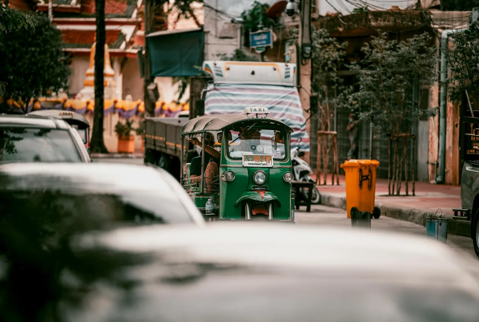 Vibrant tuk-tuk navigating through heavy Bangkok traffic, showcasing urban street life.