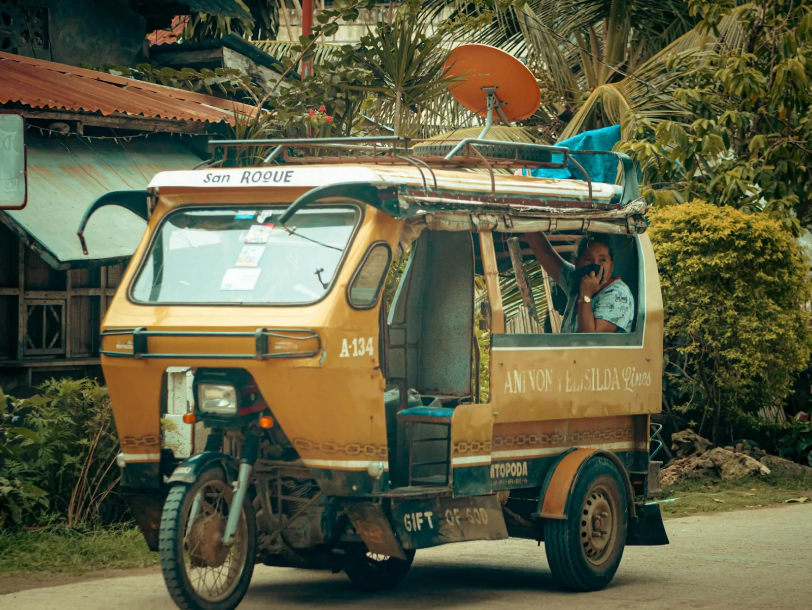 Vibrant tricycle with a driver on a tropical street, showcasing local transport.
