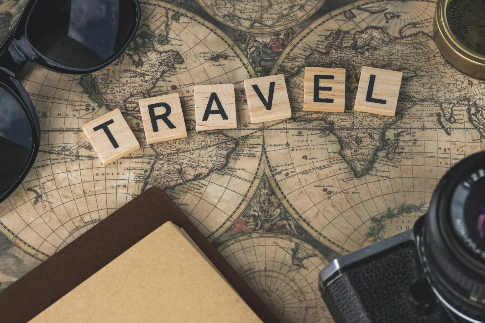 Vintage map with travel essentials like camera and sunglasses arranged in a flat lay, perfect for adventure themes.