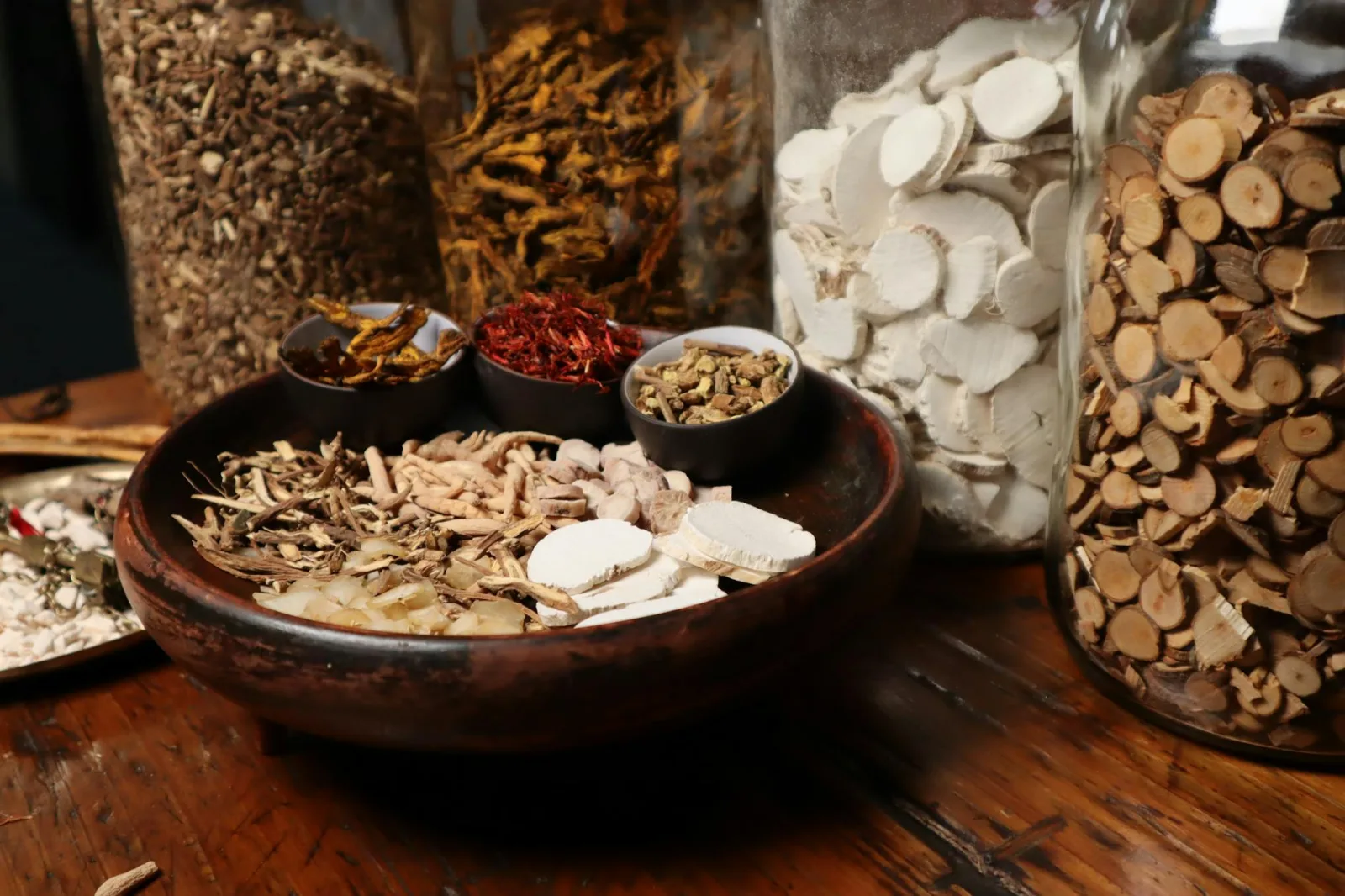 A collection of assorted traditional Chinese herbs and spices in jars and bowls.