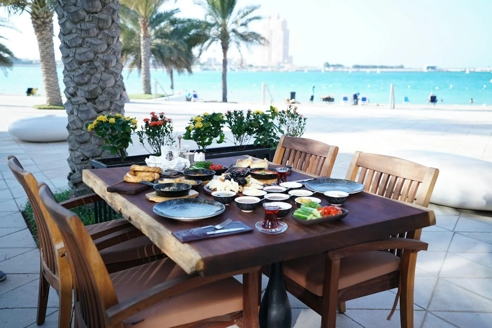 Beautiful outdoor dining setup with various dishes overlooking the sea and palm trees.